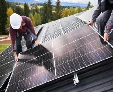 Workers installing solar panels on a roof in a scenic outdoor setting.
